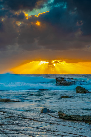 Moody sunrise seascape with clouds and sunrays at the rocky inle