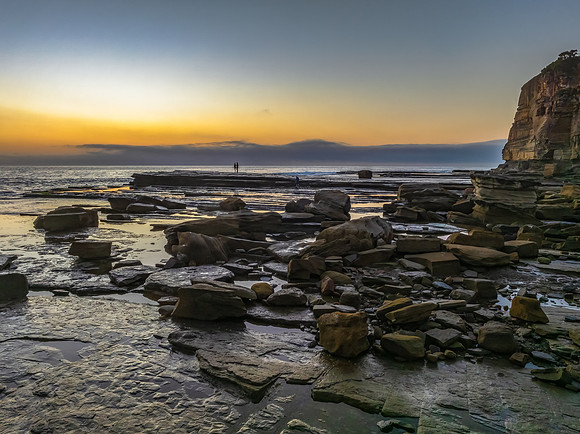 Sunrise seascape and rocky Inlet with thick fog cloud over the o