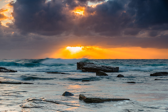 Moody sunrise seascape with clouds and sunrays at the rocky inle