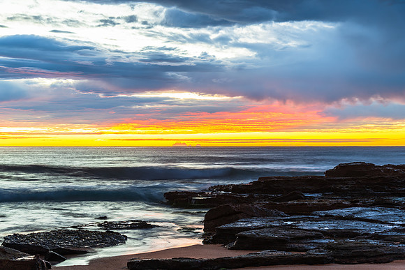 Winter sunrise by the sea shore with rain clouds