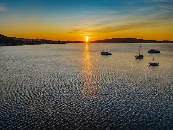 Aerial sunrise waterscape with boats and high cloud