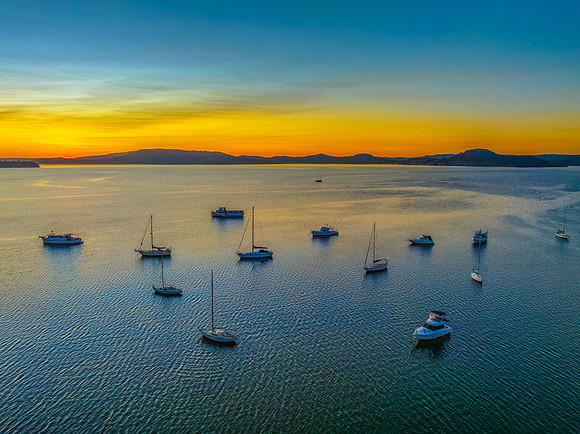 Aerial sunrise waterscape with boats and high cloud