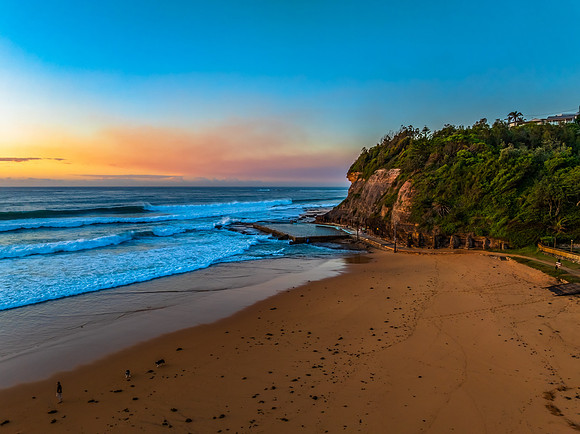 Sunrise at the beach with waves and a smattering of clouds