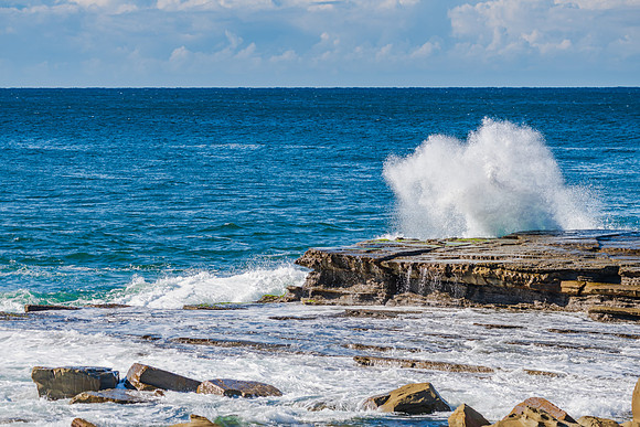 Splashes and morning seascape at rocky inlet