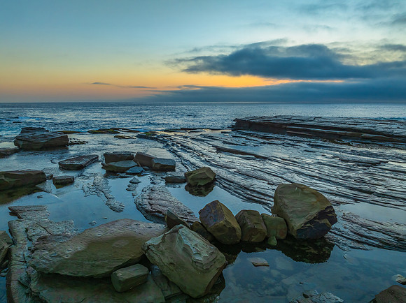 Sunrise seascape and rocky Inlet with thick fog cloud over the o