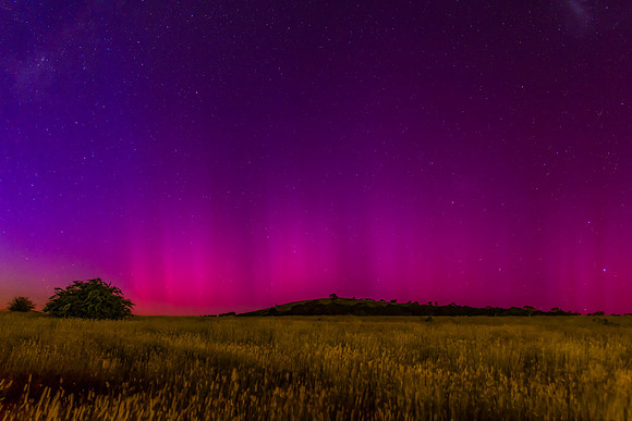 Aurora Australis display lights up the predawn sky in pinks
