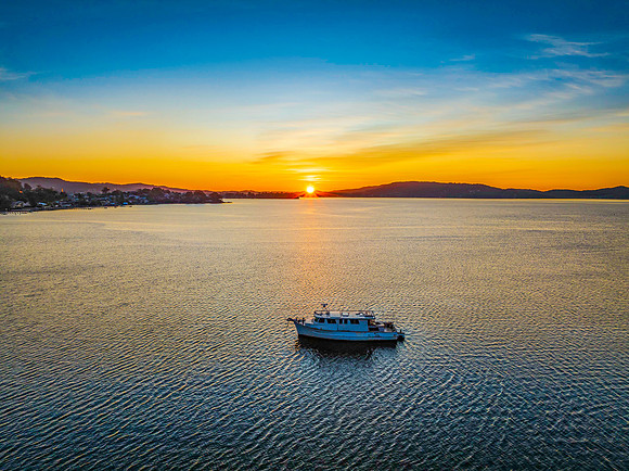 Aerial sunrise waterscape with boat and high cloud