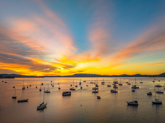 Aerial sunrise waterscape with boats and high cloud