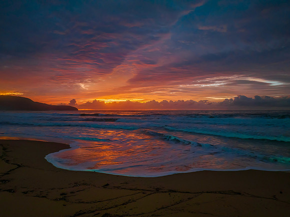Cloud covered sunrise at the seaside in pink and blue