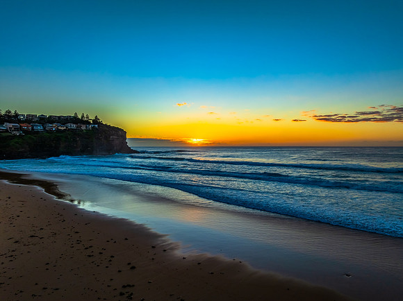 Sunrise at the beach with waves and a smattering of clouds