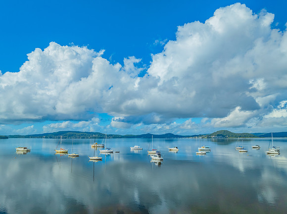Aerial views over the bay with clouds, reflections and boats