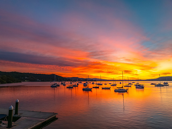 Aerial sunrise waterscape with boats and high cloud