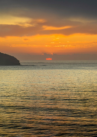 Peaceful sunrise over the ocean with small waves and clouds