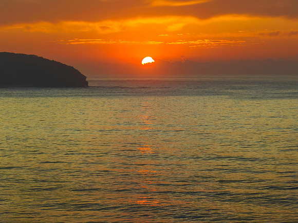 Peaceful sunrise over the ocean with small waves and clouds