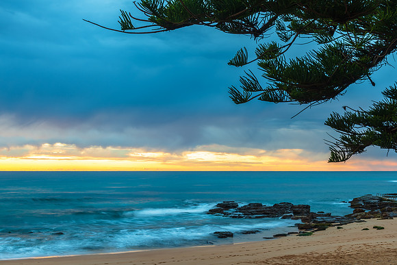 Winter sunrise by the sea shore with rain clouds
