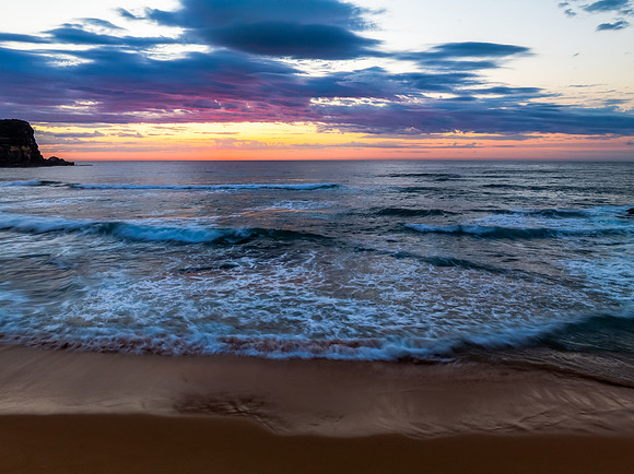 Seaside Sunrise Under a Cloud-Filled Sky