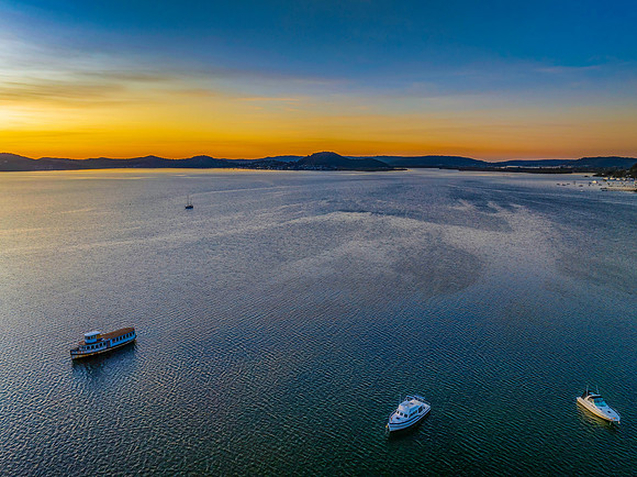 Aerial sunrise waterscape with boats and high cloud