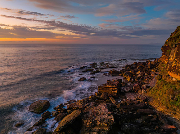 Peaceful sunrise over the ocean with small waves and clouds