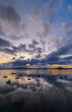 Aerial sunrise waterscape with boats, rain clouds and reflection