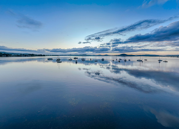 Aerial sunrise waterscape with boats, rain clouds and reflection