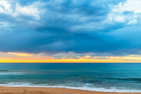 Winter sunrise by the sea shore with rain clouds