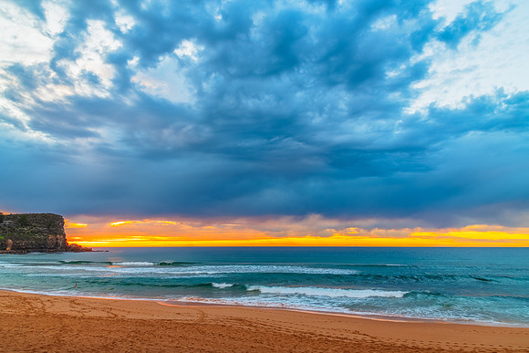 Winter sunrise by the sea shore with rain clouds
