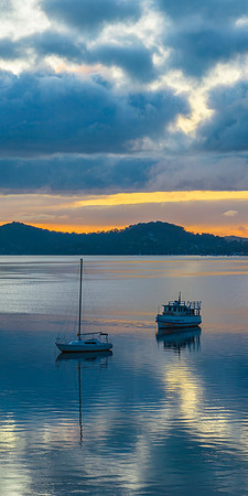 Aerial sunrise waterscape with boats, rain clouds and reflection