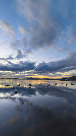 Aerial sunrise waterscape with boats, rain clouds and reflection