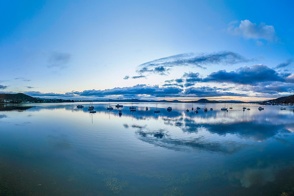 Aerial sunrise waterscape with boats, rain clouds and reflection