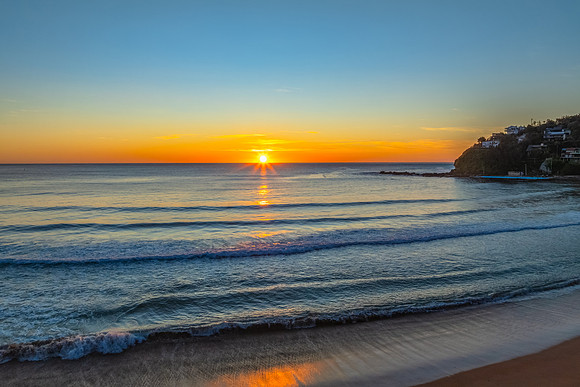 Ocean Sunrise Under Clear Skies with Orange Horizon