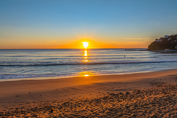 Ocean Sunrise Under Clear Skies with Orange Horizon