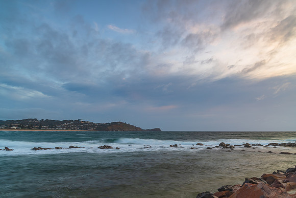 Cloud covered sunrise seascape with rocks