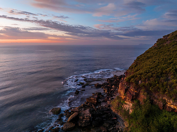 Peaceful sunrise over the ocean with small waves and clouds