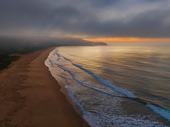 Peaceful sunrise over the ocean with small waves and clouds