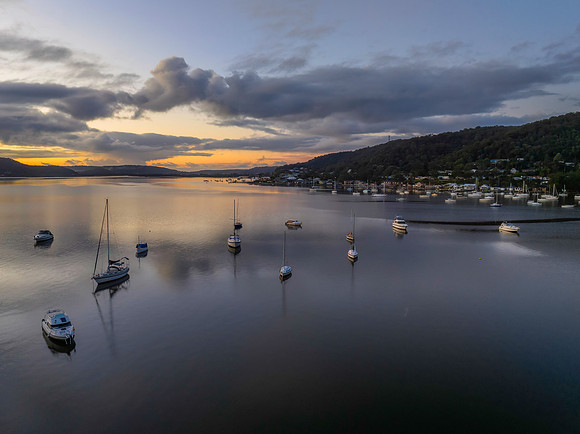 Aerial sunrise waterscape with boats, rain clouds and reflection