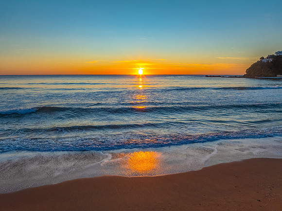 Ocean Sunrise Under Clear Skies with Orange Horizon