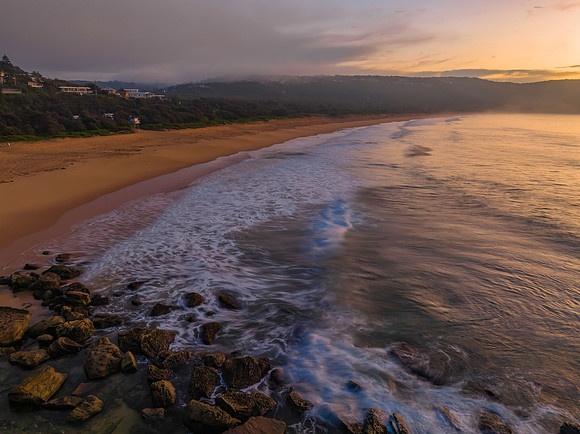 Peaceful sunrise over the ocean with small waves and clouds