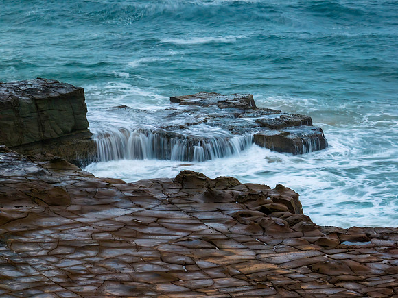 Top down seascape, water cascades and rock platform