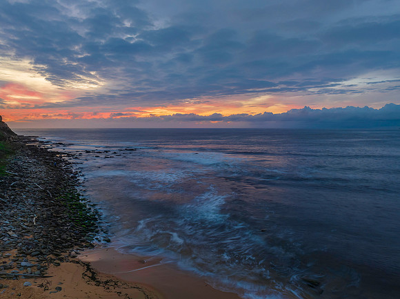 Pastel cloud covered sunrise seascape