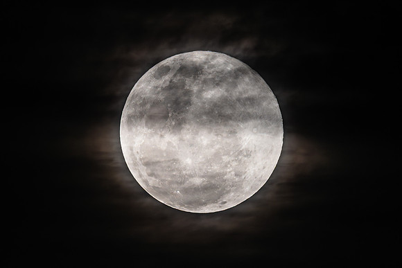 The Harvest Moon supermoon rises in the cloud covered sky