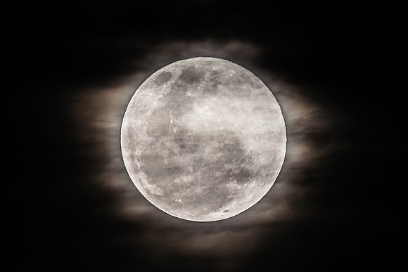 The Harvest Moon supermoon rises in the cloud covered sky