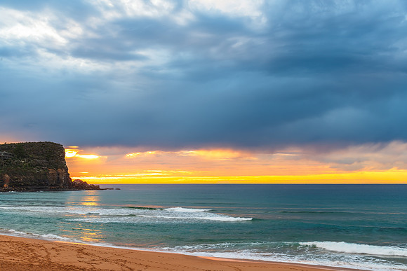 Winter sunrise by the sea shore with rain clouds