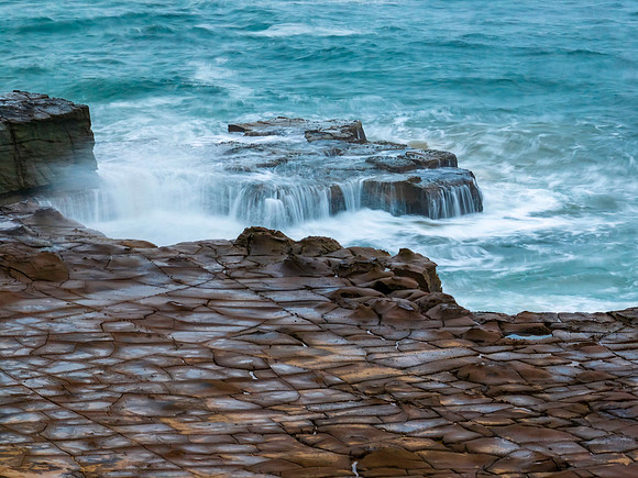 Top down seascape, water cascades and rock platform