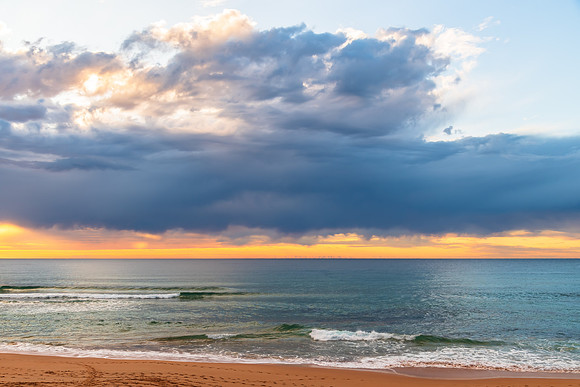 Winter sunrise by the sea shore with rain clouds