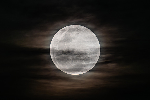 The Harvest Moon supermoon rises in the cloud covered sky