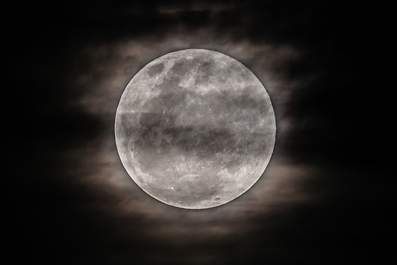 The Harvest Moon supermoon rises in the cloud covered sky