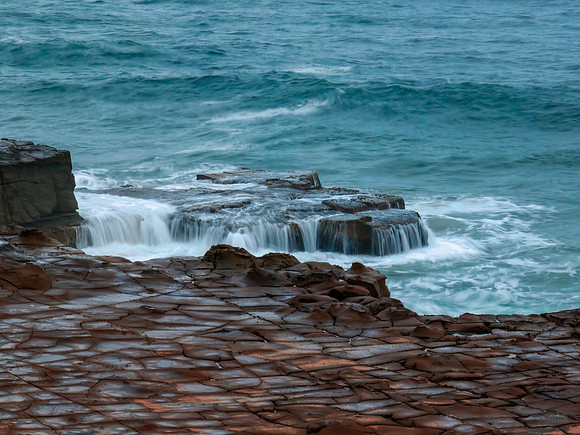 Top down seascape, water cascades and rock platform