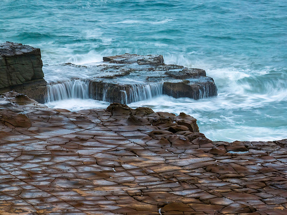 Top down seascape, water cascades and rock platform