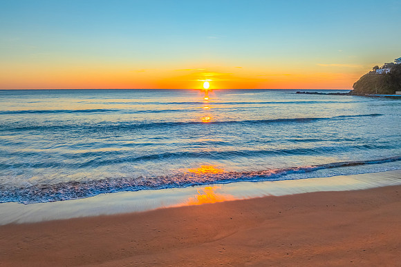 Ocean Sunrise Under Clear Skies with Orange Horizon