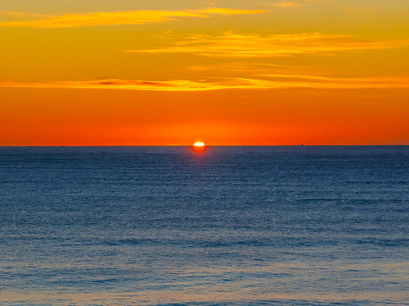 Ocean Sunrise Under Clear Skies with Orange Horizon